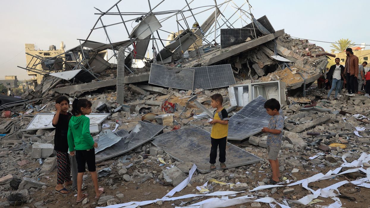 Children stand with bombed solar panels in Gaza.