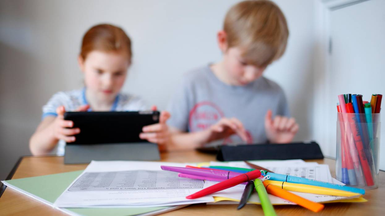 Children use computer tablets at a desk.