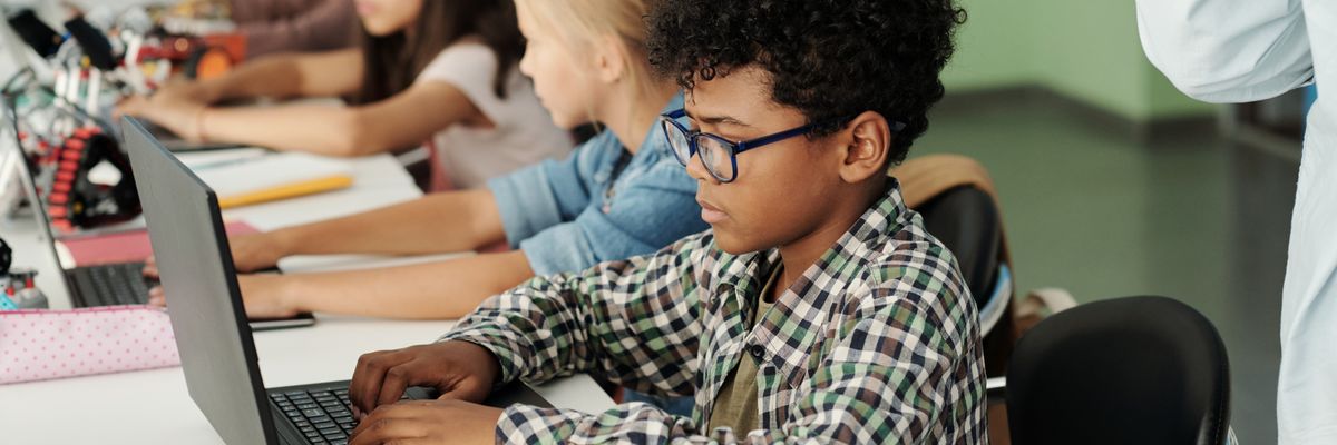 Children use laptops in a classroom.