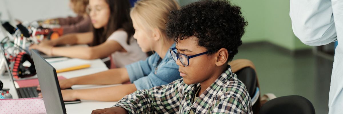 Children use laptops in a classroom.