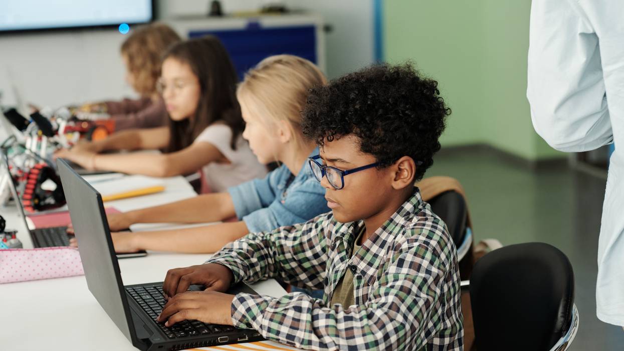 Children use laptops in a classroom.