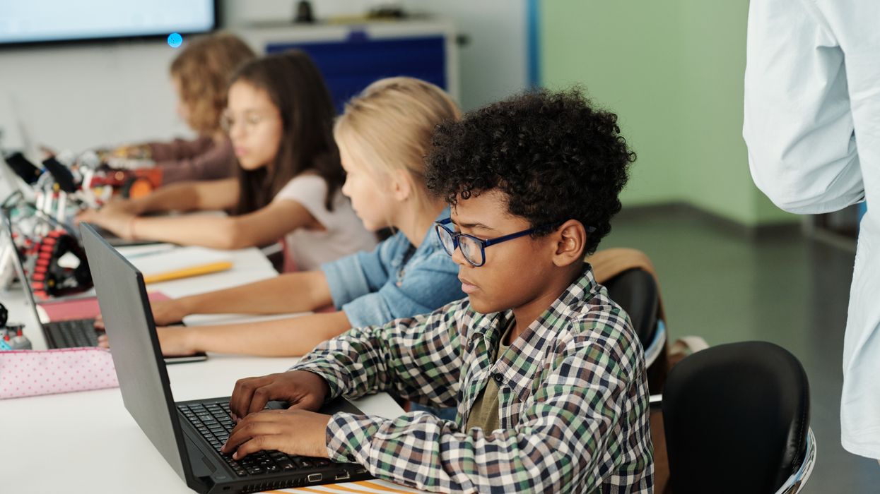 Children use laptops in a classroom.