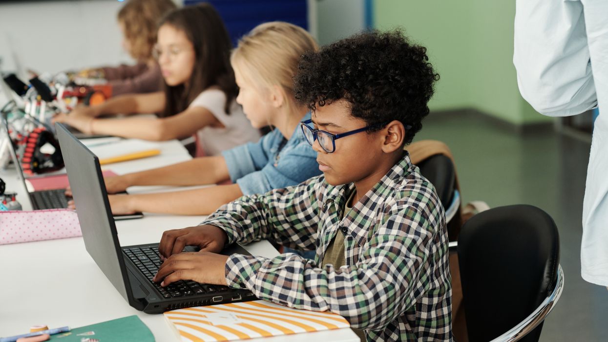 Children use laptops in a classroom.