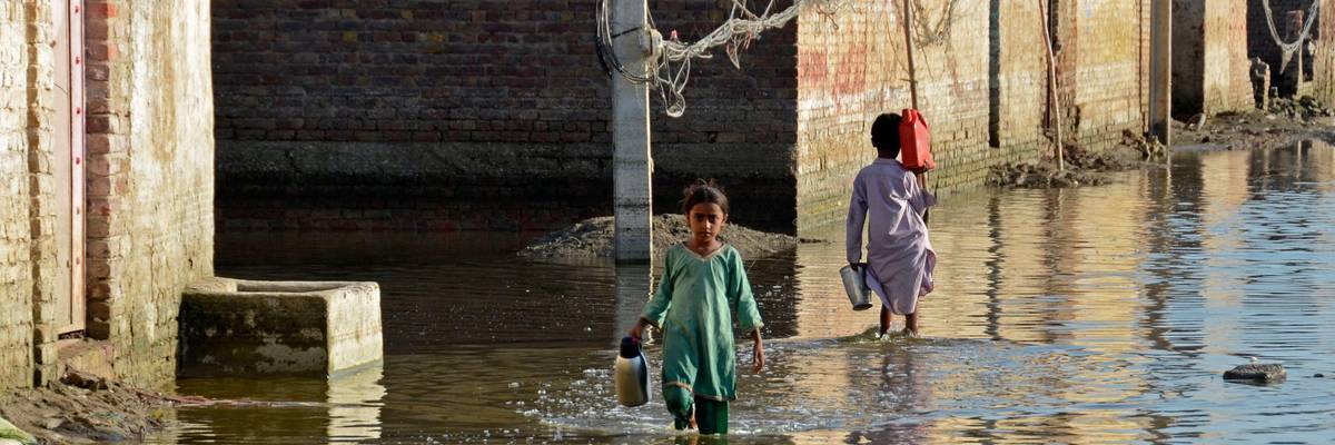 Children wade through a flooded street in the Jaffarabad district of Pakistan's Balochistan province on October 4, 2022.