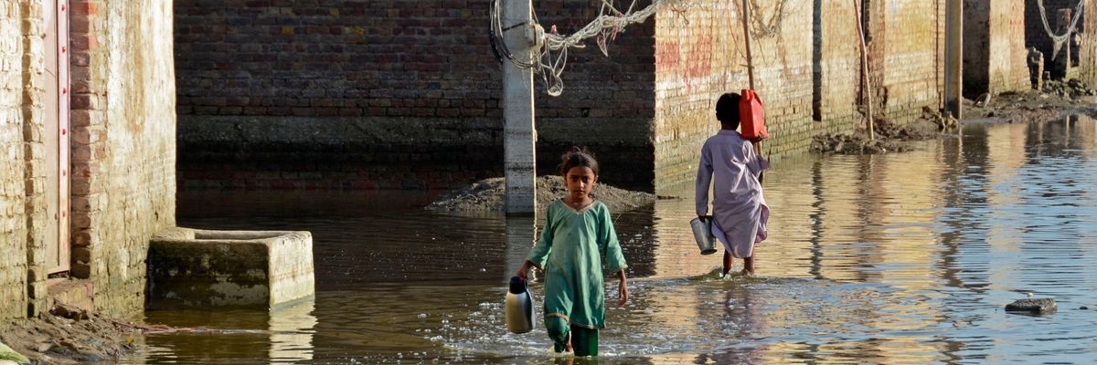 Children wade through a flooded street in the Jaffarabad district of Pakistan's Balochistan province on October 4, 2022.