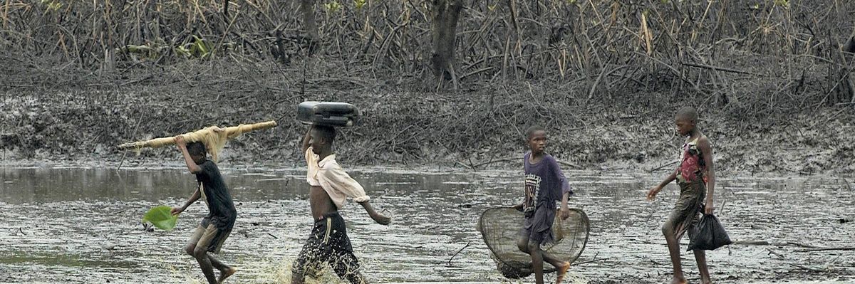 children walk through oil-covered mangrove
