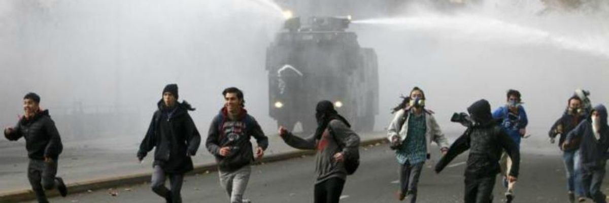 Chilean students protesting the government's lack of attention to their calls for free education run from a water cannon, 2014