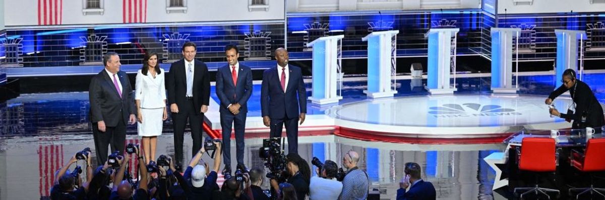 Chris Christie, Nikki Haley, Ron DeSantis, Vivek Ramaswamy, and Tim Scott stand on a debate stage in front of podiums. 