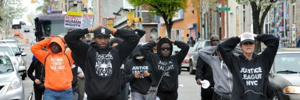 Citizens and groups such as the Justice League of NYC walk along the streets of West Baltimore in protest against the police following the death of Freddie Gray who died while in the hospital.