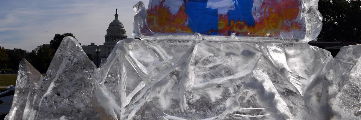 Climate activists display a burning Facebook logo in a melting block of ice