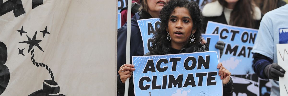 Climate activists gather to demand President Biden stop the Willow Project with blue signs.