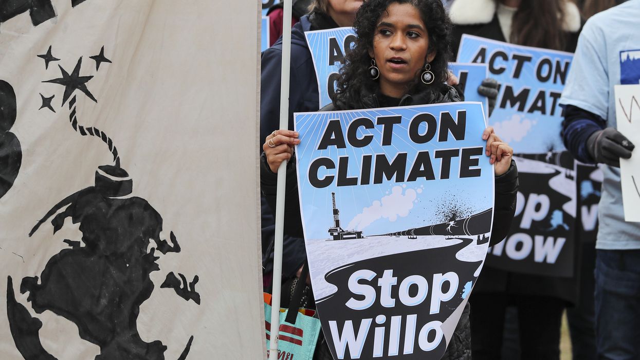 Climate activists gather to demand President Biden stop the Willow Project with blue signs.