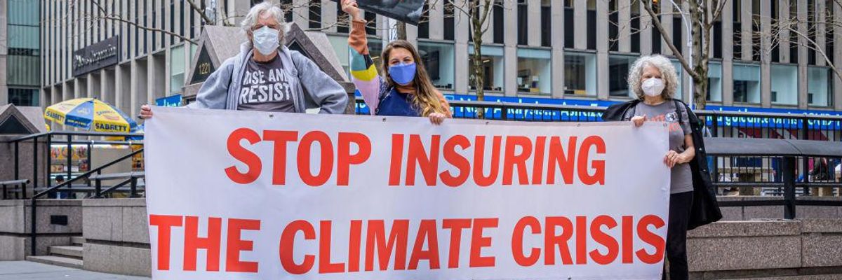 Climate activists hold a sign saying, "Stop insuring the climate crisis."