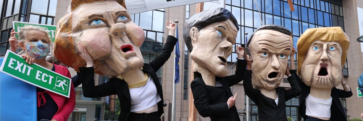 Climate activists stage a demonstration in front of the E.U. Council building to highlight the threat of the Energy Charter Treaty (ECT) to the planet as they wear huge model heads of European Commission President Ursula von der Leyen, Dutch Prime Minister Mark Rutte, French President Emmanuel Macron, and then-German Chancellor Angela Merkel in Brussels, Belgium on July 6, 2021.