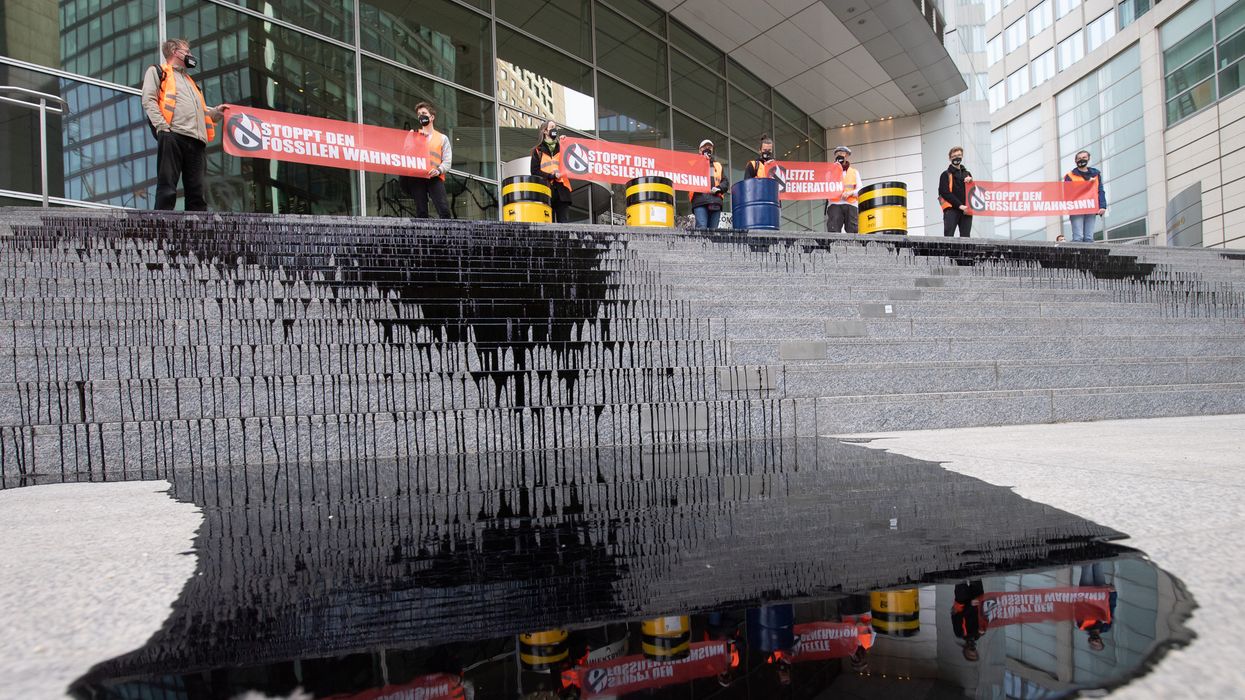 Climate activists standing on steps of Commerzbank in Germany with oil-like liquid dripping down the steps.