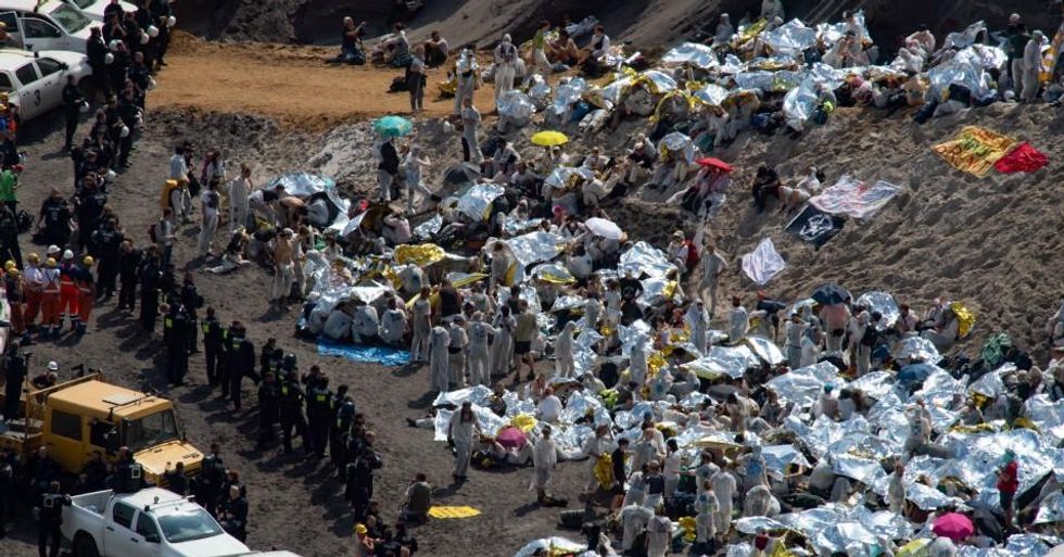 Climate justice activists protect themselves from the sun with rescue blankets after they have been encased in the Garzweiler opencast mine by police officers and vehicles of employees of the opencast mine after breaking through a police blockade. The protests for more climate protection in the Rhineland continue. (Photo: Frederico Gambarini/picture alliance via Getty Images)