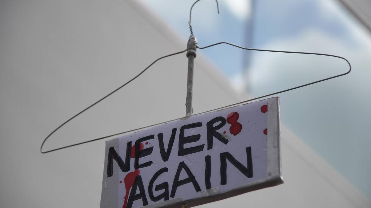 coat hanger sign reading "Never again" to protest abortion ban.