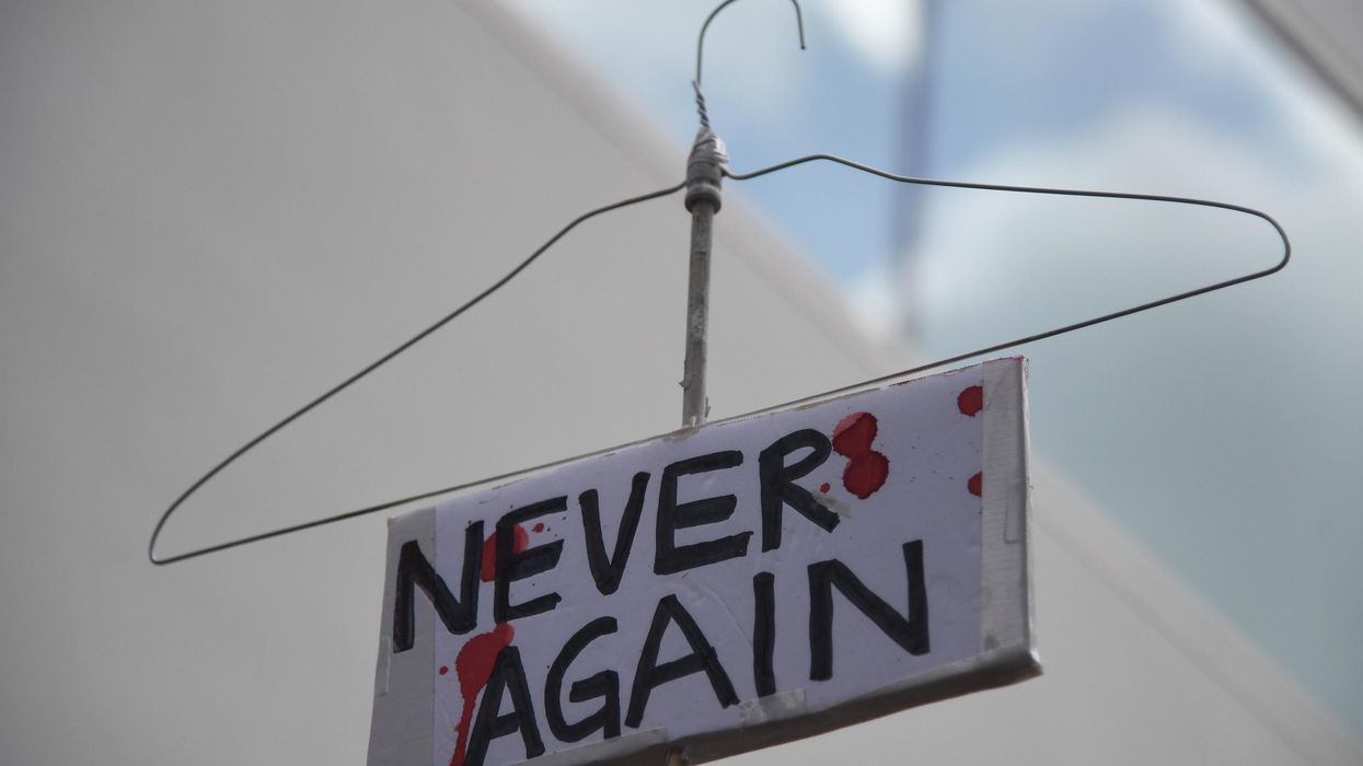 coat hanger sign reading "Never again" to protest abortion ban.