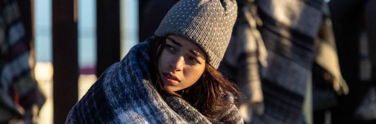 Colombian immigrant Gisele, 18, bundles up after spending the night camped alongside the U.S.-Mexico border fence