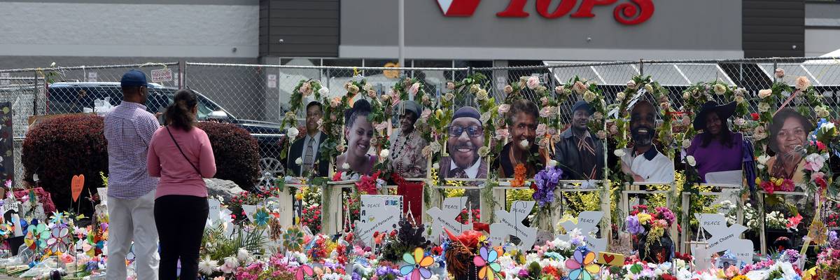 Community members pay respects to the victims of a shooting