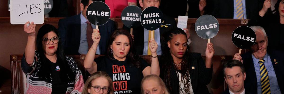Congressional Democrats hold signs during Trump's speech.