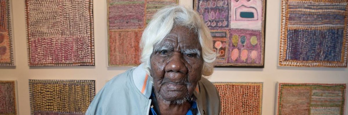 Daisy Loongkoonan stands in front of her paintings.