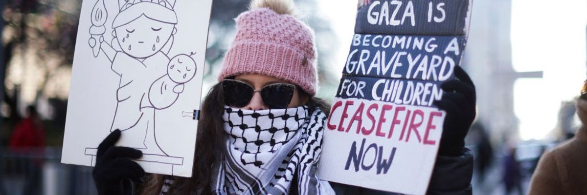 Demonstrator holding picture of Statue of Liberty and sign reading "Ceasefire Now"