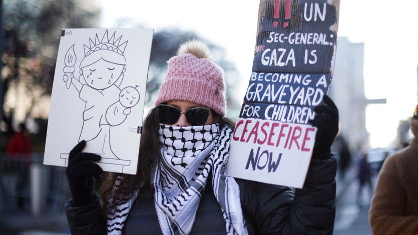 Demonstrator holding picture of Statue of Liberty and sign reading "Ceasefire Now"