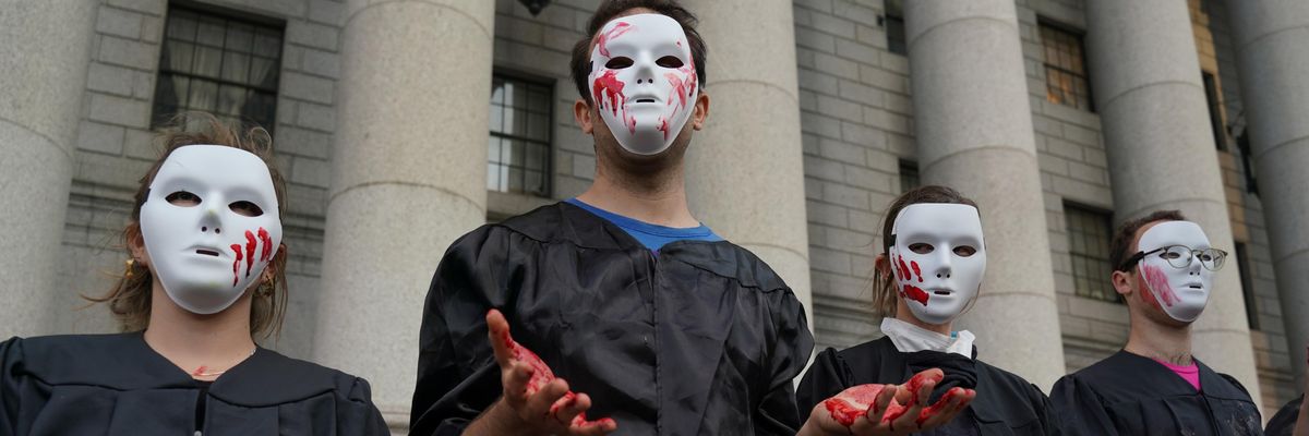 Demonstrators dressed as Supreme Court Justices with blood-soaked hands