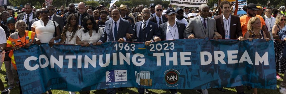 Demonstrators hold a banner reading, "1963-2023: Continuing the Dream."