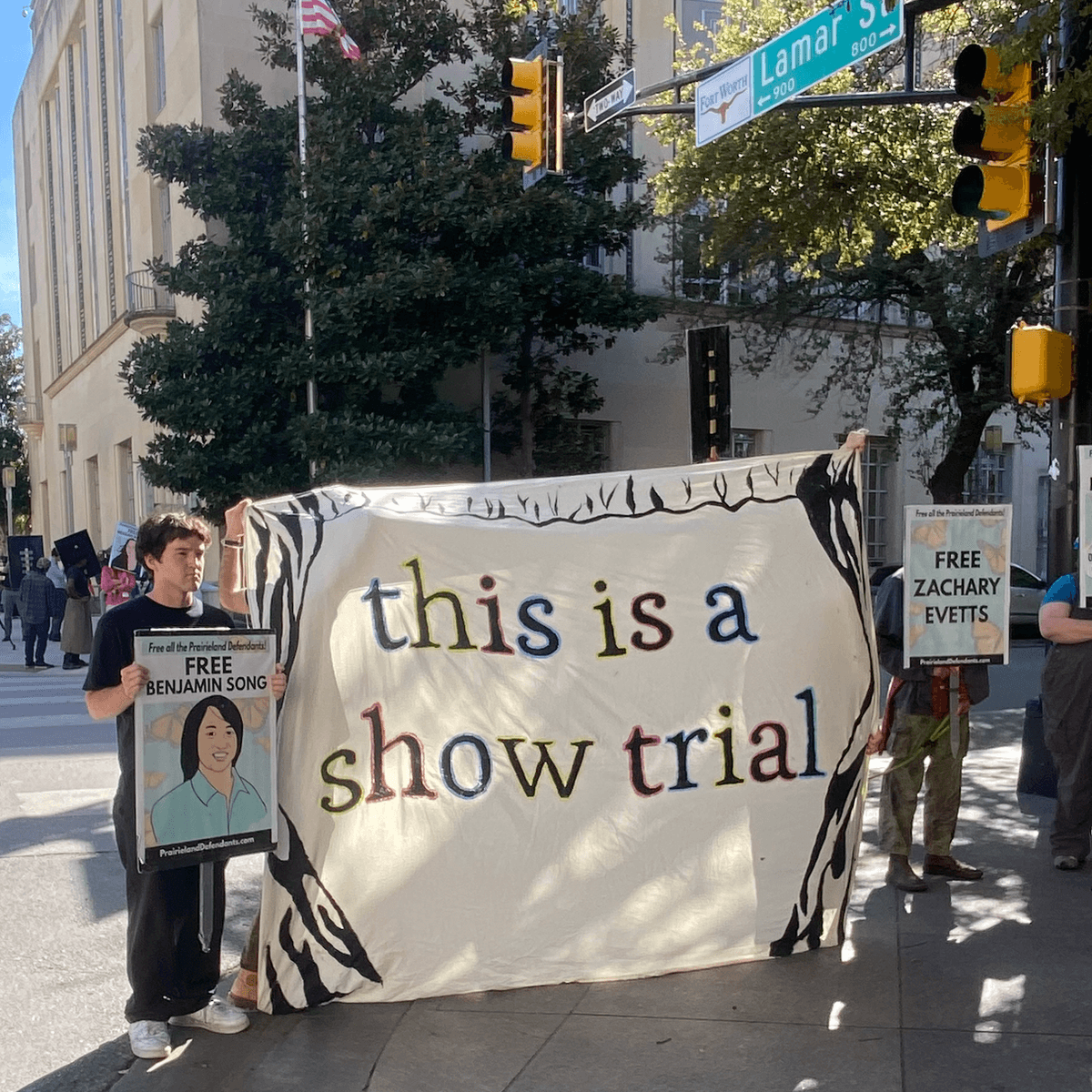 Demonstrators hold a banner reading "this is a show trial" outside court during the trial of Prairieview anti-ICE protesters