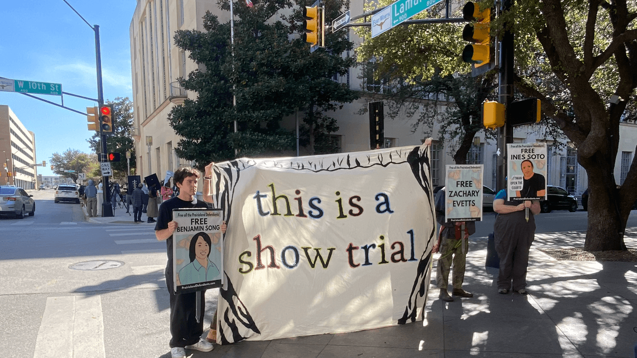 Demonstrators hold a banner reading "this is a show trial" outside court during the trial of Prairieview anti-ICE protesters