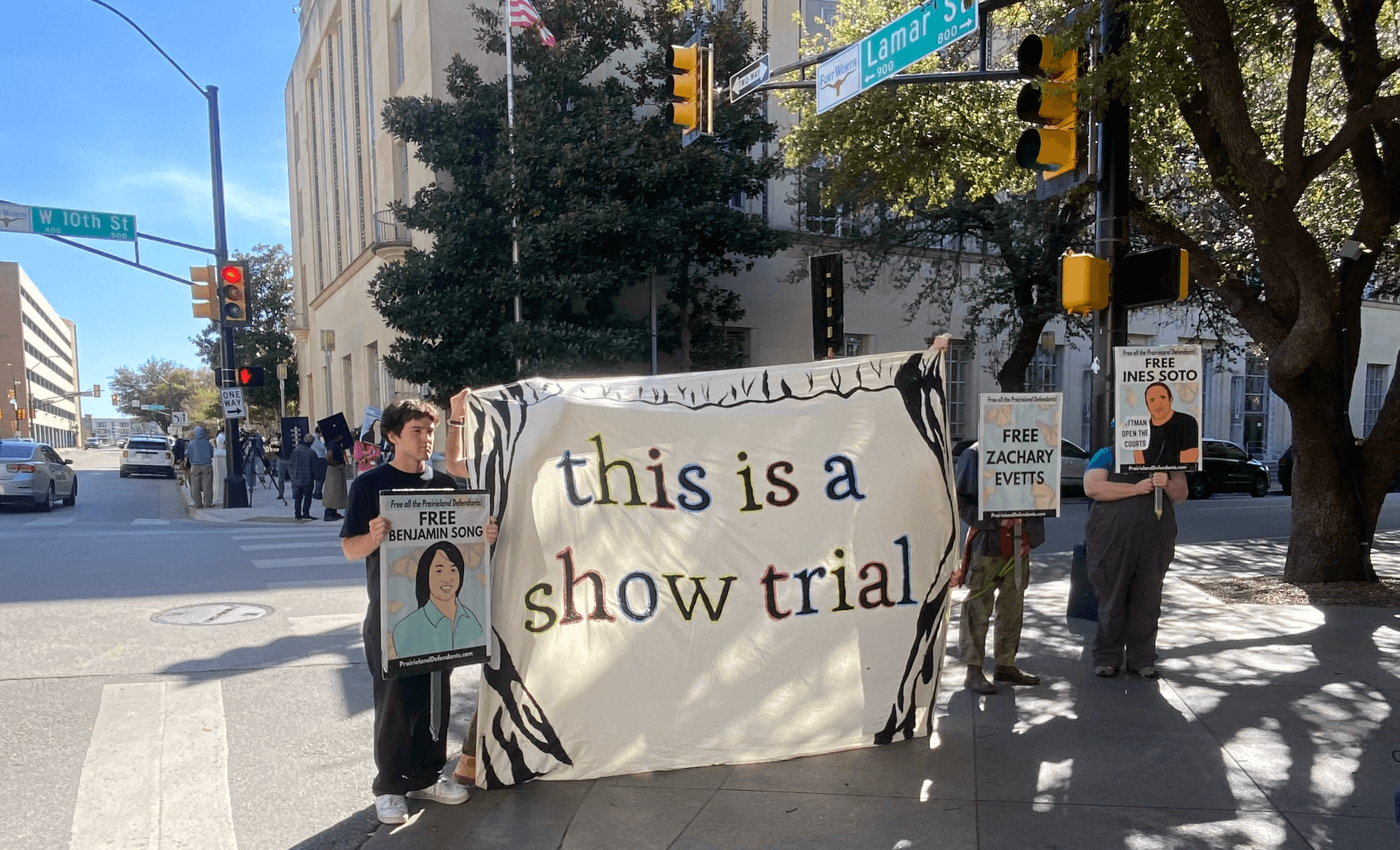 Demonstrators hold a banner reading "this is a show trial" outside court during the trial of Prairieview anti-ICE protesters