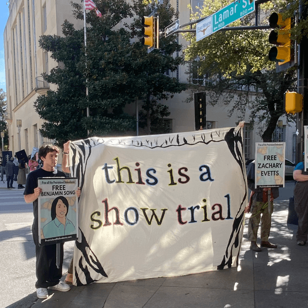 Demonstrators hold a banner reading "this is a show trial" outside court during the trial of Prairieview anti-ICE protesters