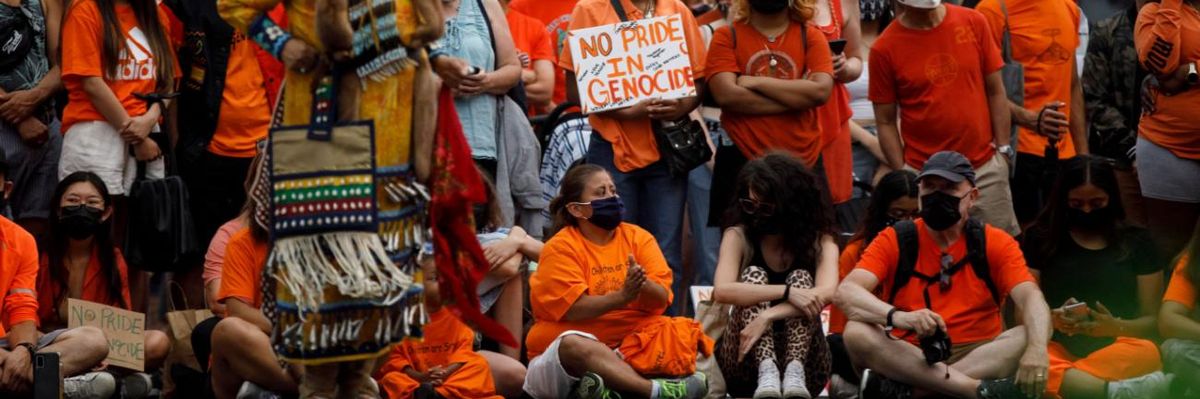 Demonstrators hold a sign reading "No pride in genocide" on Canada Day