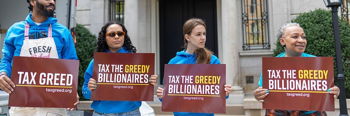 Demonstrators hold signs outside Jeff Bezos' house in a protest against U.S. tax policies