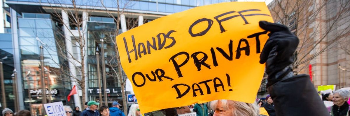 Demonstrators hold signs protesting Elon Musk's Department of Government Efficiency