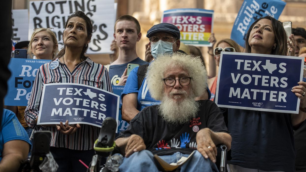 Demonstrators hold up signs at a rally at the Texas State Capitol on June 20, 2021 in Austin.