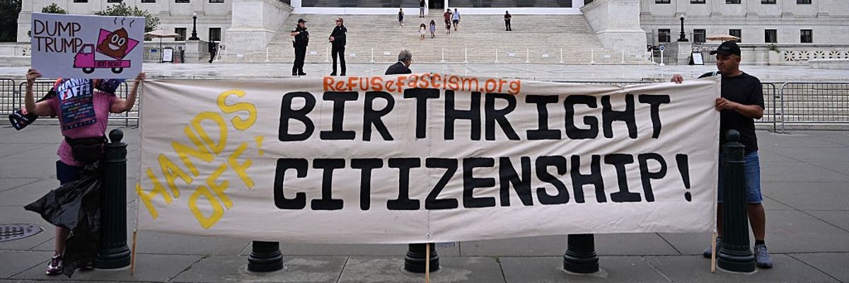Demonstrators hold up signs opposing President Donald Trump and his attack on birthright citizenship