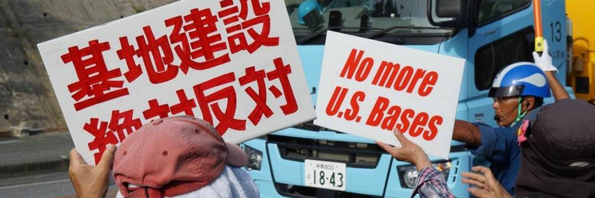 Demonstrators hold up white signs with red letters.