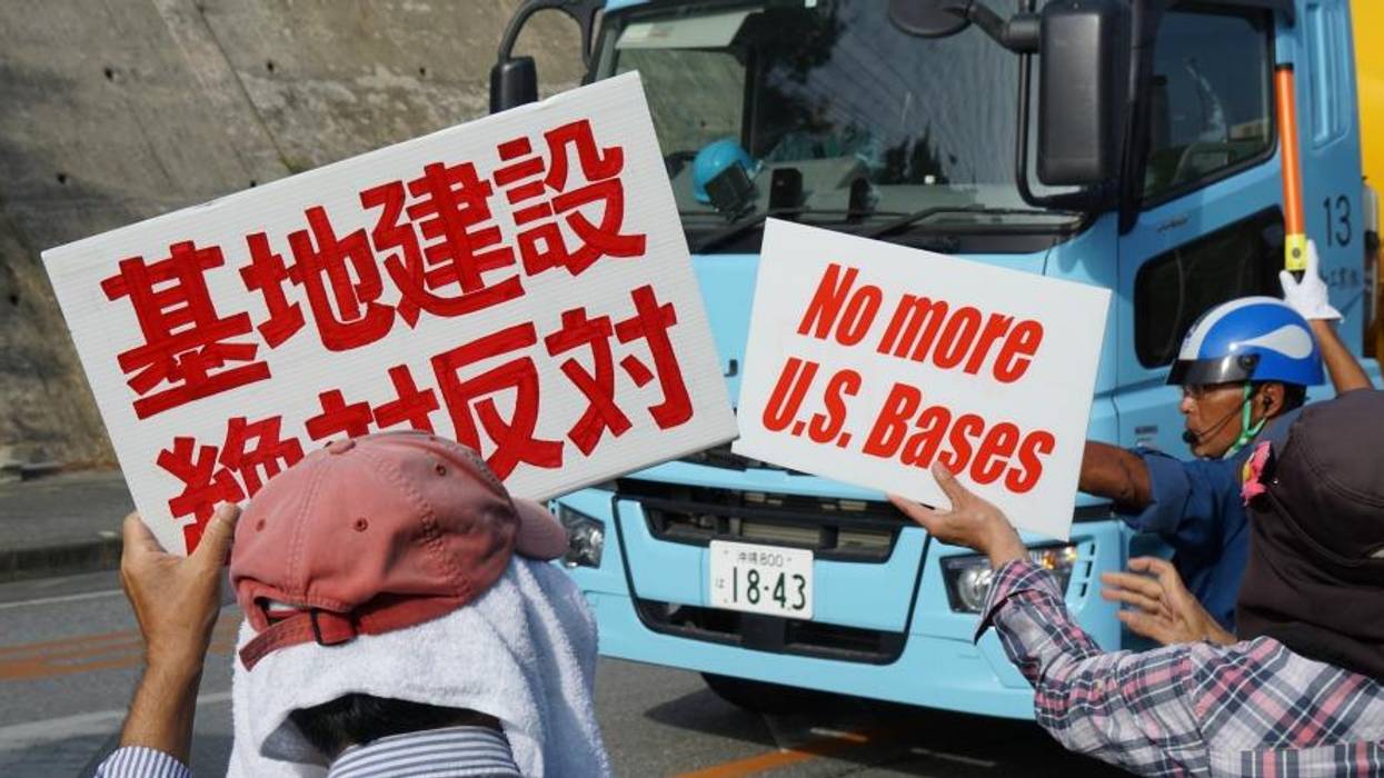 Demonstrators hold up white signs with red letters.