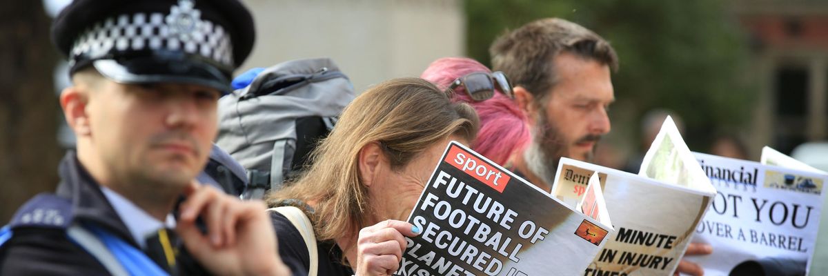Demonstrators read spoof newspapers