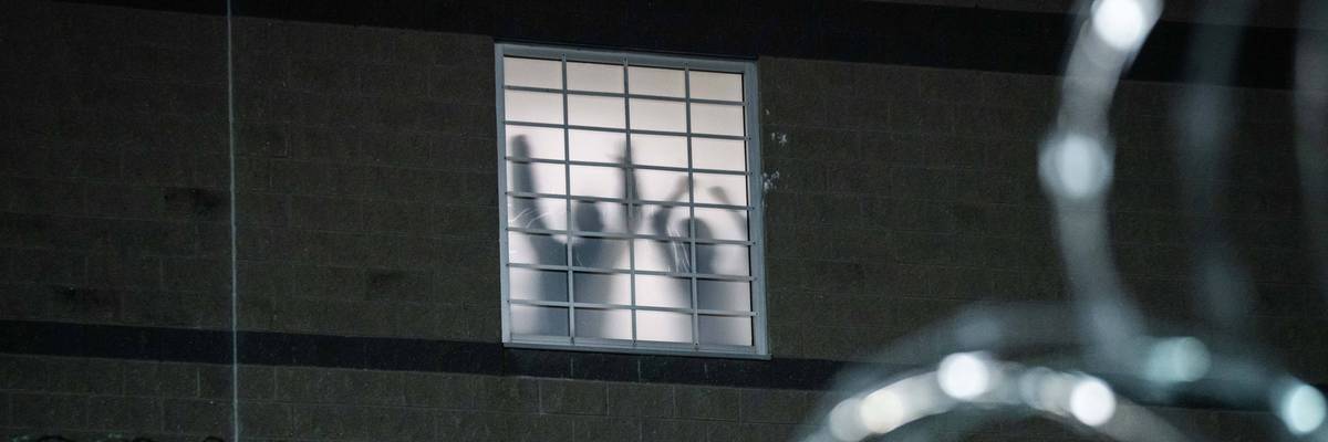 Detainees stand by a window in an ICE lockup
