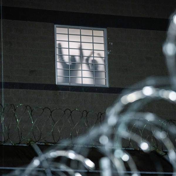 Detainees stand by a window in an ICE lockup
