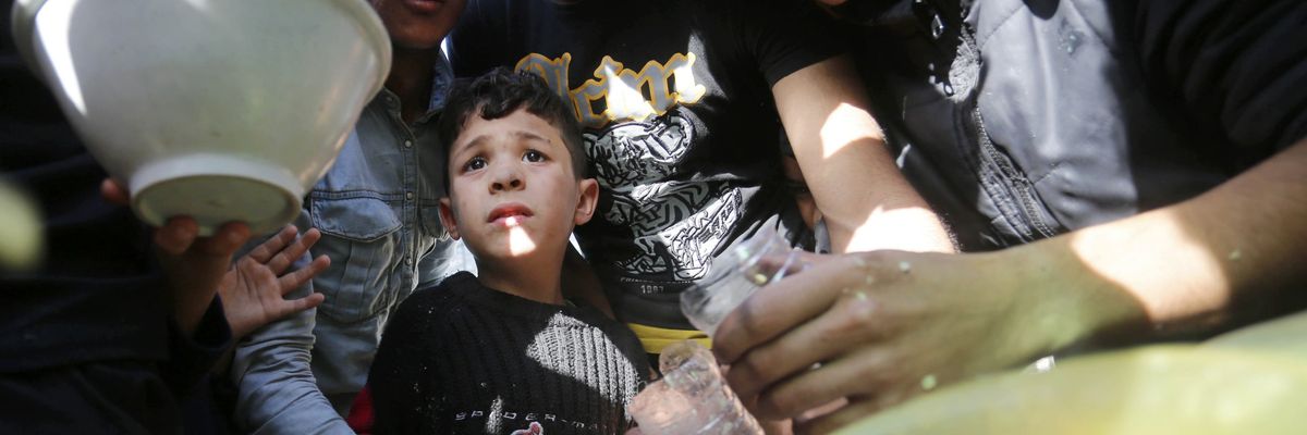 Displaced Palestinians in a tent camp in Deir al Balah wait for soup distributed by volunteers