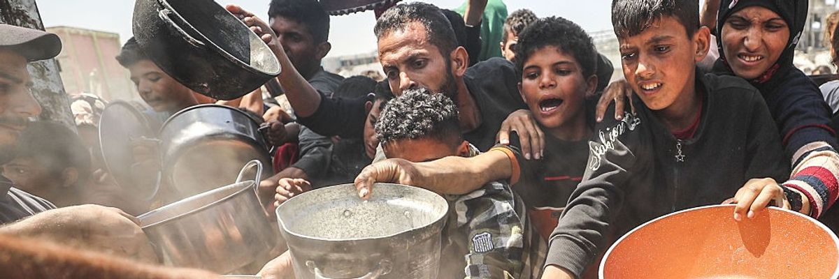 Displaced Palestinians, including children, wait with empty pots