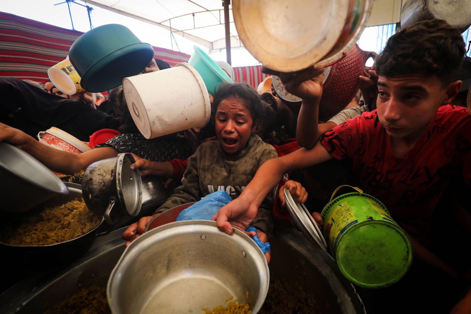 displaced-palestinians-including-numerous-children-holding-empty-containers-and-cooking-pots-crowd-around-a-community-aid-dist.jpg?id=68485704&width=5000&height=3334&coordinates=0%2C0%2C0%2C0