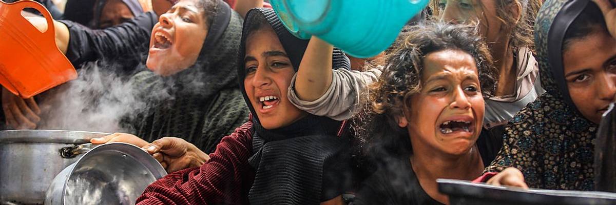 Displaced Palestinians queue for hot meals in Gaza
