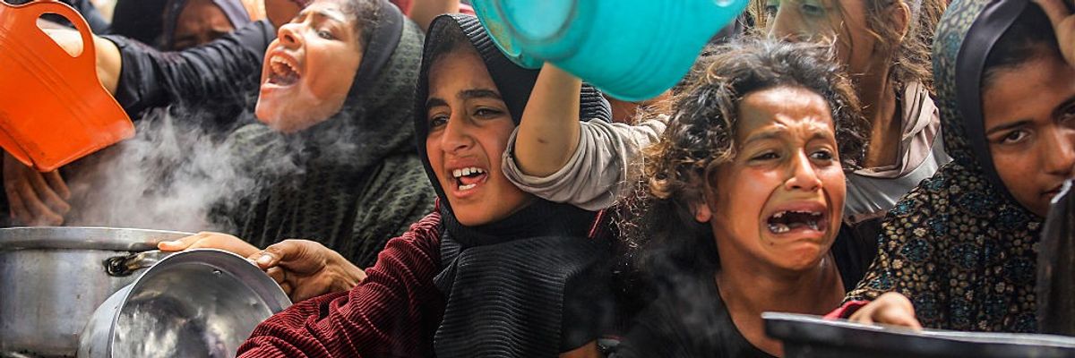 Displaced Palestinians queue for hot meals in Gaza