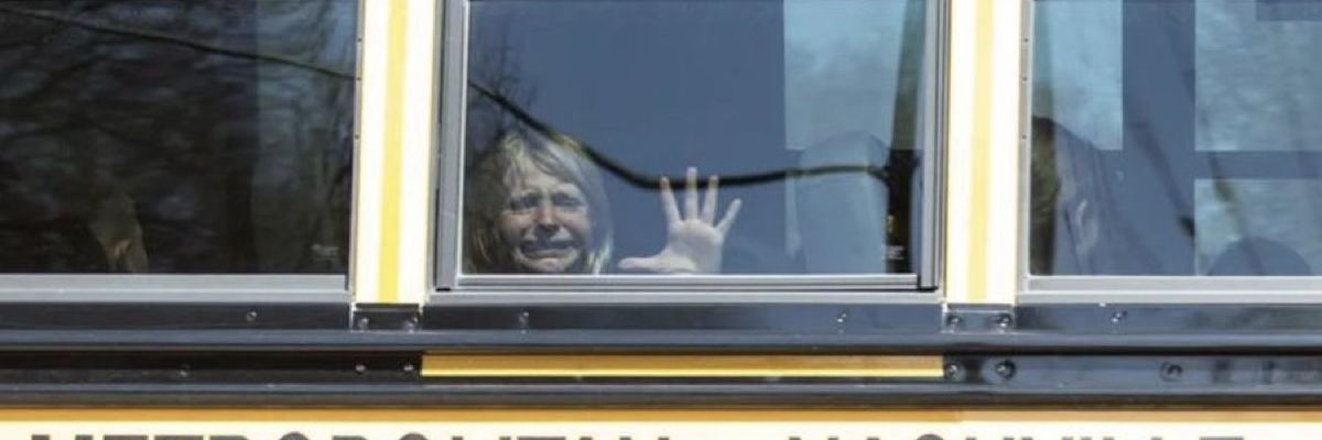 Distraught child looks out window of school bus after Nashville school shooting.